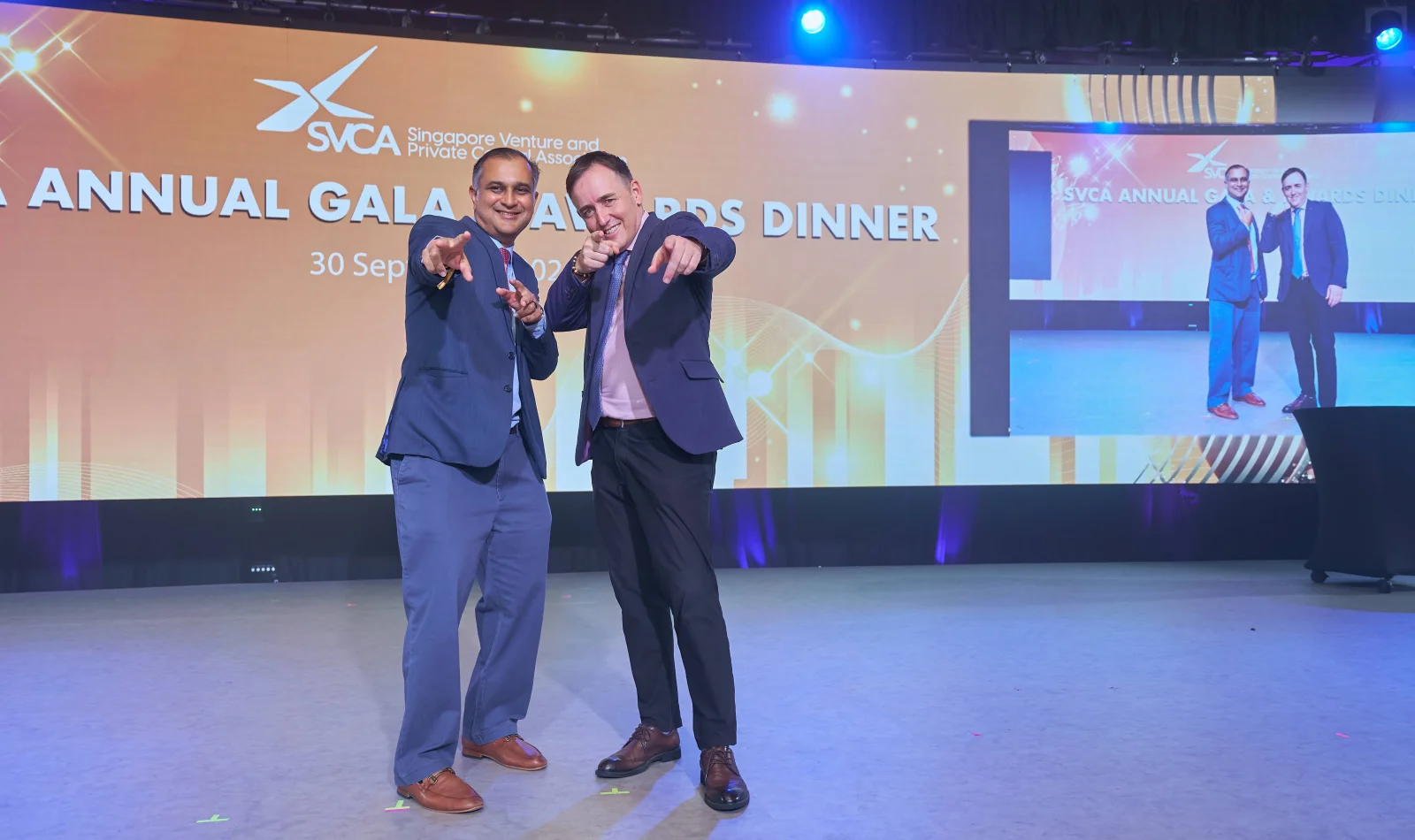 Two guests pose at the SVCA gala with their earlier photograph displayed on the venue screen